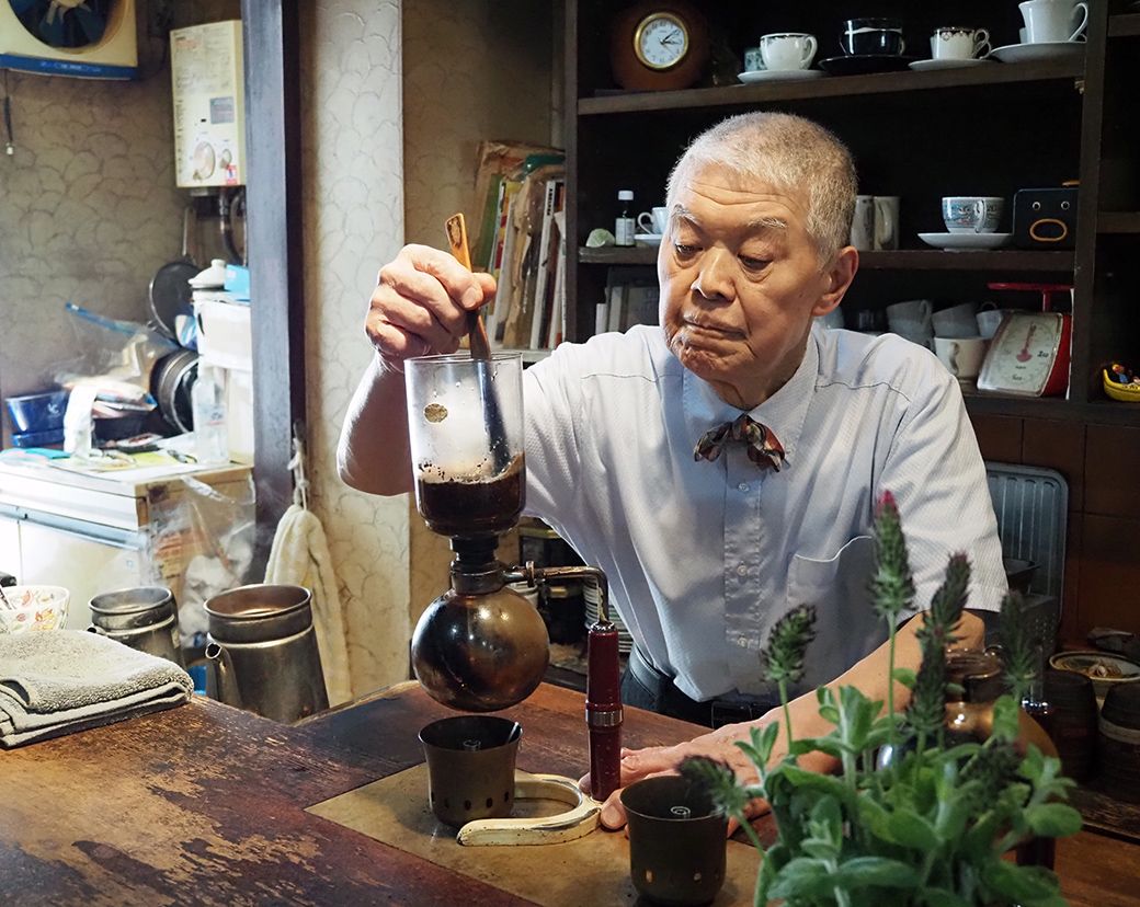 サイフォンでコーヒーを淹れる河合さん。フラスコの中に湯を入れ、コーヒー粉をつけこみ一気に抽出する（著者撮影）
