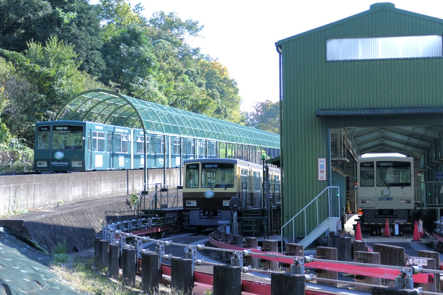 運行中のV2編成と基地内のV3編成・V1編成（記者撮影）