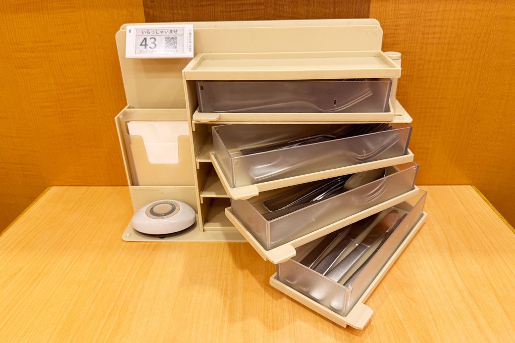 現在のサイゼリヤのセルフオーダーシステム。カトラリーボックス左上のQRコードを使用して顧客のスマホからオーダーすることで、タブレットの導入コストを削減（筆者撮影）