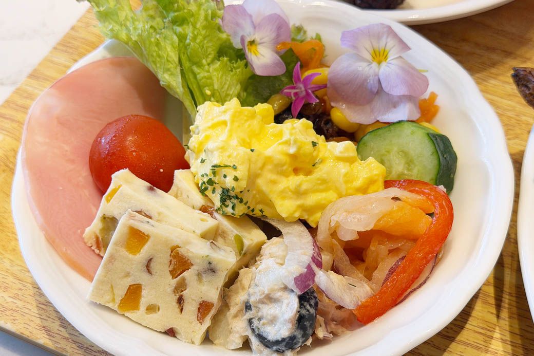 サラダを取り分けたお皿。カラフルなメニューが多く、グリーンサラダにエディブルフラワーが入っていることもあり、華やかに仕上がった（写真：筆者撮影）