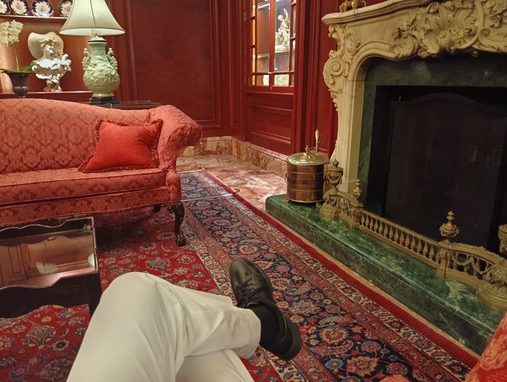 ロビーのソファー、暖炉の前で小休憩する、ユニクロのパンツとワークマンの靴を履いた筆者（筆者撮影）