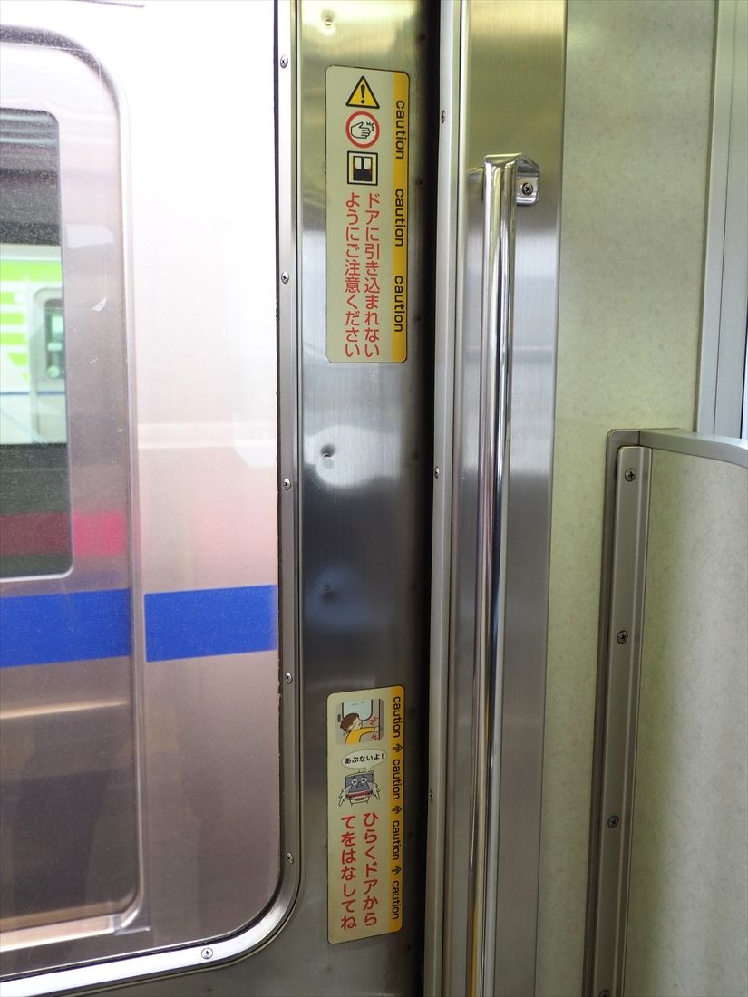 ドアに貼られた「引き込まれ防止」の注意ステッカー（記者撮影）