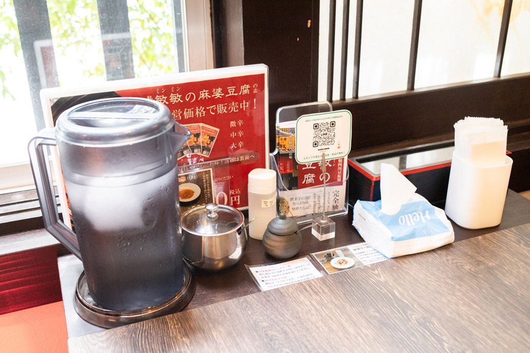 各テーブルにはたっぷりの冷えた水、ミックス塩、葉ニンニク辣油、赤山椒、ティッシュが置かれている（筆者撮影）