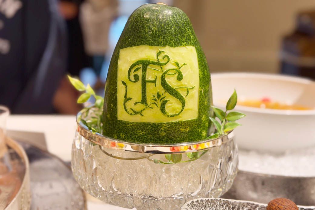 デザートエリアにディスプレイされた、フルーツカービング。ファンタジースプリングスのロゴが描かれている（写真：筆者撮影）