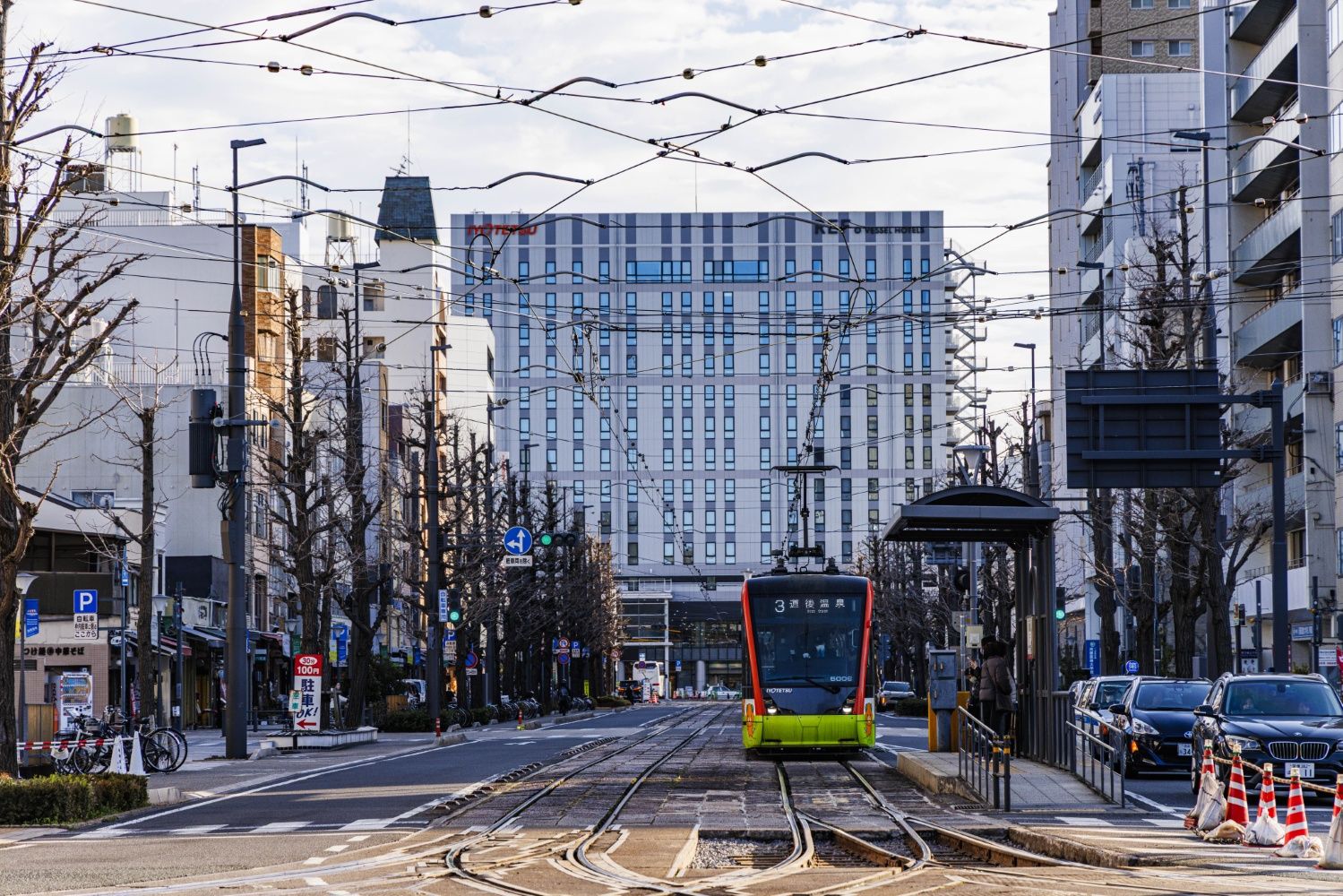 松山城のお堀端を目指して走る伊予鉄市内電車。バックに見えるのは松山市駅のターミナルビル（撮影：鼠入昌史）