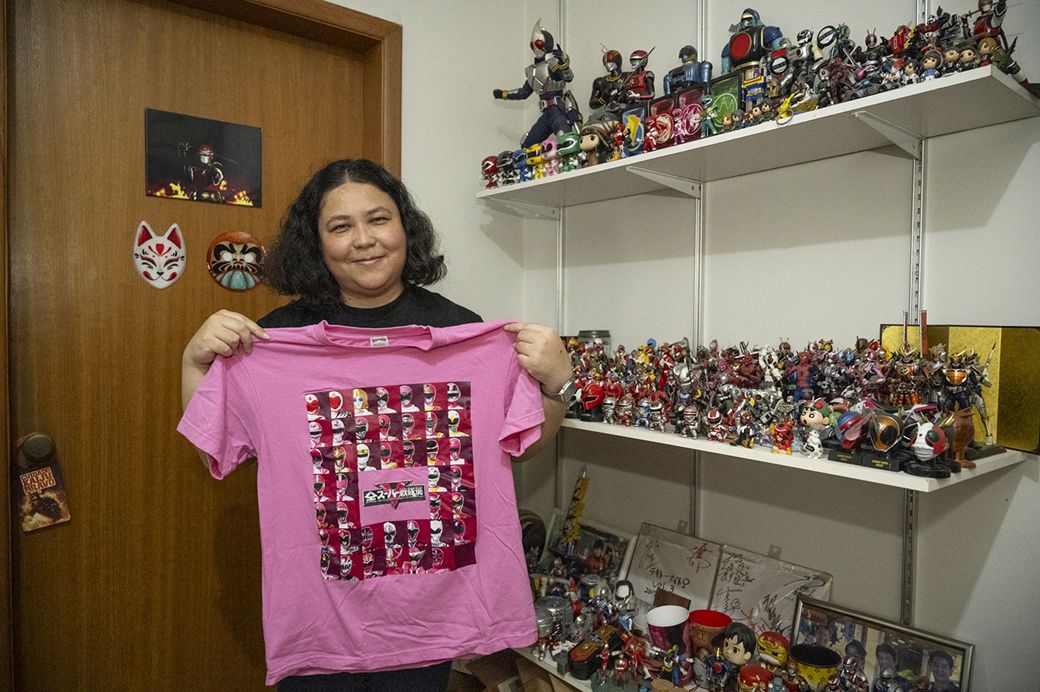 自宅で多数の特撮ヒーローのフィギュアとともに。手にするのはトクツアーで訪れた全スーパー戦隊展Tシャツ（写真：筆者撮影）