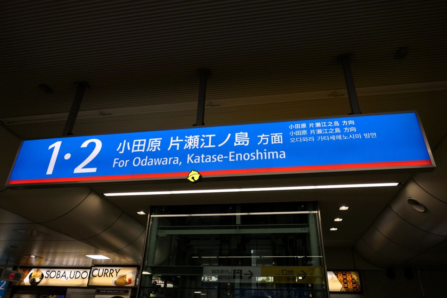 駅構内の案内看板。長方形から飛び出した「鈴」が光っている（記者撮影）