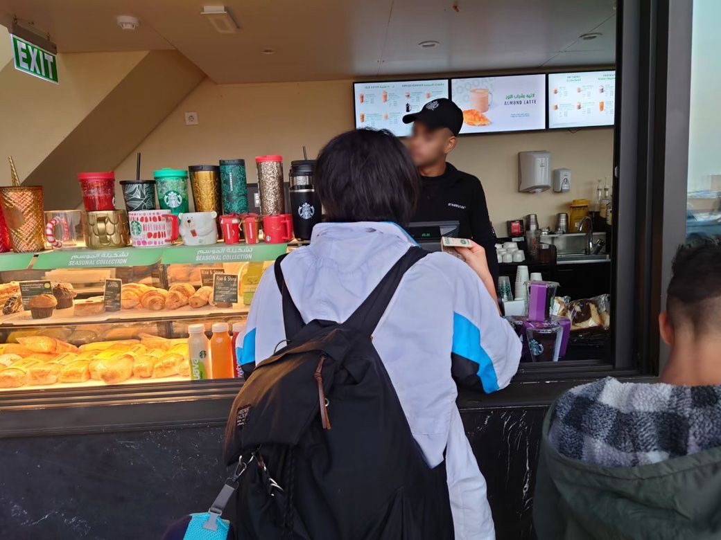 2022年に2泊4日、バッグ1個でエジプトに渡航した際、空港のスターバックスでコーヒーを買う筆者。早朝と夜間は寒かったので、YONEXのアウターを着て活動した（筆者撮影）