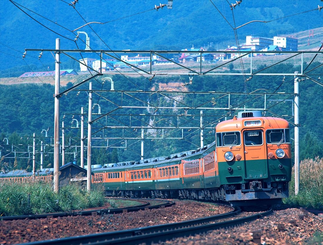 上越線の岩原スキー場前付近を走る165系の急行「佐渡」。グリーン車2両にビュフェも連結した全盛期の編成（撮影：南正時）