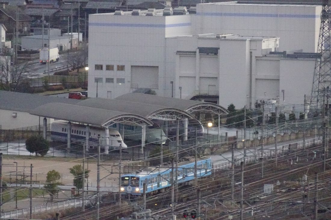 鉄道総研風洞技術センターに保存された新幹線試作車の前を走る近江鉄道の電車（撮影：南正時）