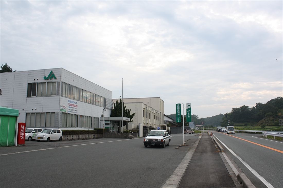 石見今福駅の予定地だった場所は島根県道5号に取り込まれている。近くには農協の施設などがある（筆者撮影）