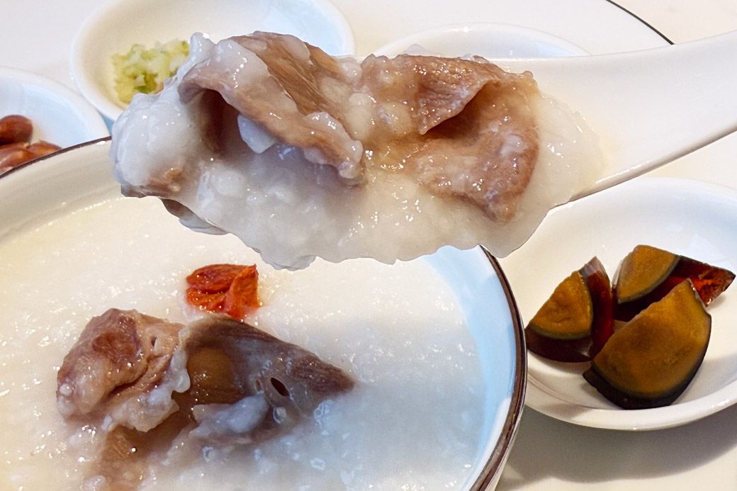 チャイニーズブレックファストのビーフ入り中華粥。塩をまぶした落花生やピータンで味変を楽しみながらいただく（写真：筆者撮影）