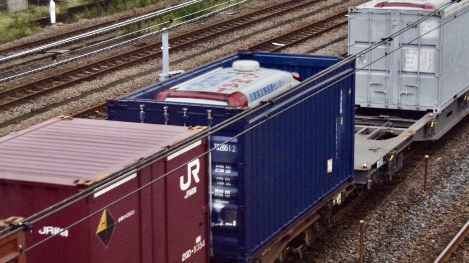 オープントップコンテナで鉄道輸送される救急車。災害時は貨物列車で救急車を輸送することもある。