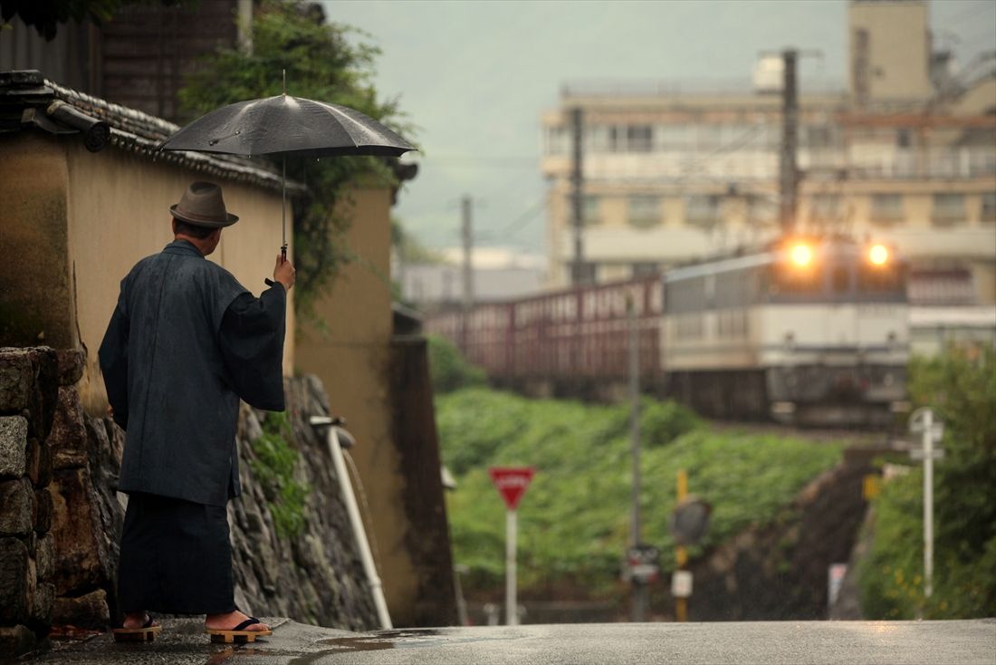 伯備線を行くEF64形0番台牽引の貨物列車。左の人物は筆者。伯備線の登場する「寅さん」をイメージしてみた（写真：坪内政美）
