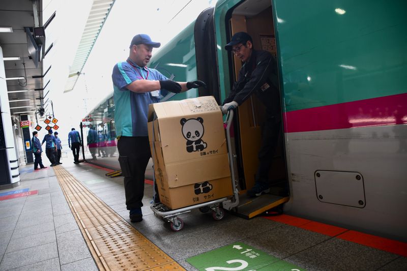 車内から台車に載せられた荷物を運び出す（記者撮影）