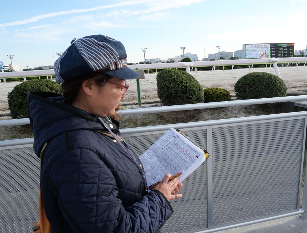 スポーツ報知の誌面に視線を落とす志賀さん。お尻中心の分析といえど、予想するときは至って真剣（筆者撮影）