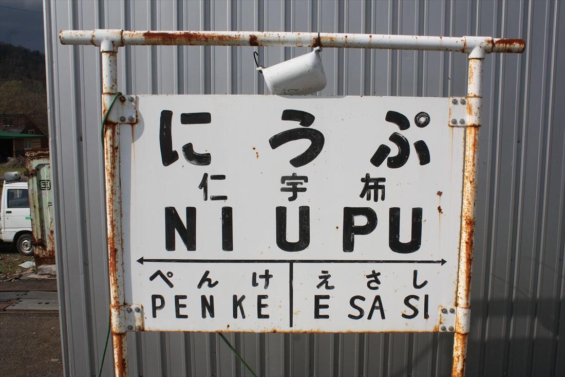トロッコ王国美深に残る仁宇布駅の駅名標。下部の隣駅表示に未成区間の駅が書き加えられているが、なぜか「きたみおおまがり」ではなく終点の「えさし」だ（筆者撮影）