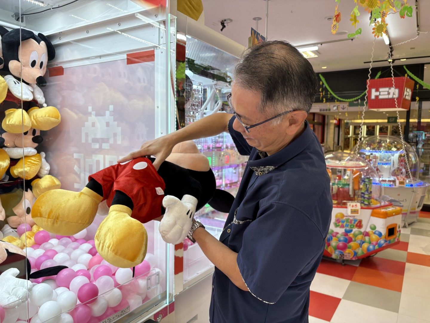 お金を入れる前に、景品の重心の位置を考える小山さん（写真：筆者撮影）