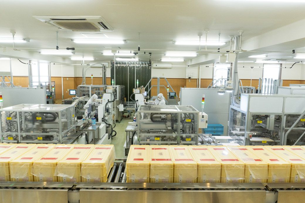 保管箱に入った揖保乃糸がコンベアで運ばれ、私たちが商品棚で手にする6束入りのパッケージに包装される（筆者撮影）