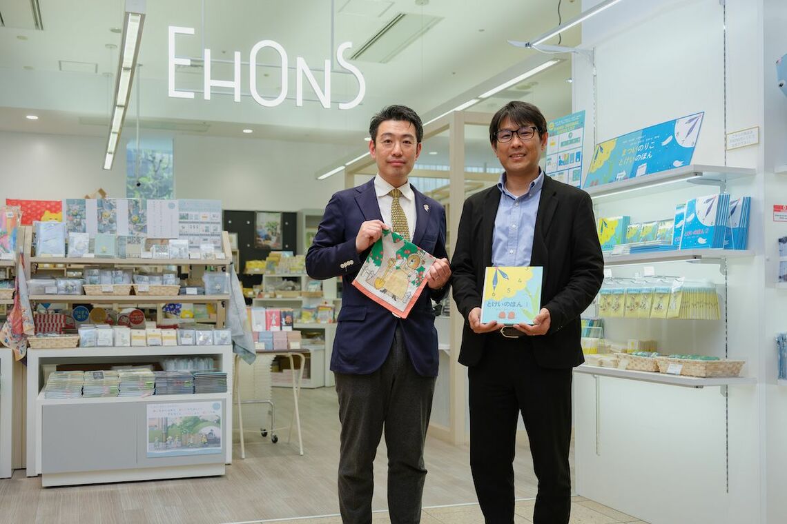 「EHONZ」の前で、おすすめの絵本グッズを持つ丸善丸の内店店長の篠田晃典氏（右）と店舗開発に携わる中﨑悠人氏（左）