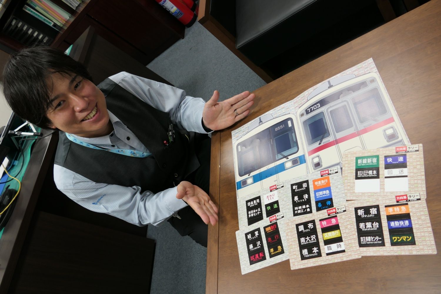 方向幕カードラリーの企画に携わった新百合ヶ丘駅駅員の讓原淳さん。台紙には「小田急8000形」と「京王7000系」（記者撮影）