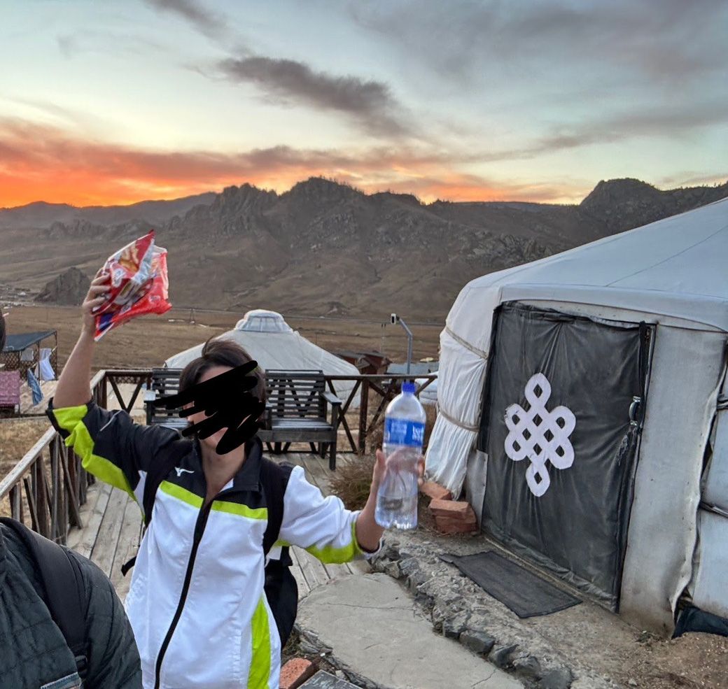 モンゴルで「かっぱえびせん」を握りしめる筆者。アホヅラなので黒塗りしました。ちなみにかっぱえびせんは、このテントを所有しているオーナー夫婦にプレゼントしました（筆者撮影）