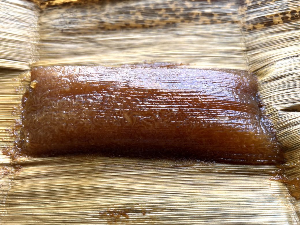 竹皮の包みを紐解くと、艶のあるべっこう色に輝いているあくまきが出てくる（筆者撮影）