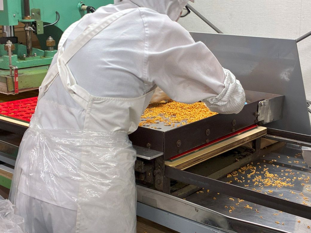 ヤッターめんの製造工程。まずは細かく砕いた麺を、容器に手で流し込む（筆者撮影）