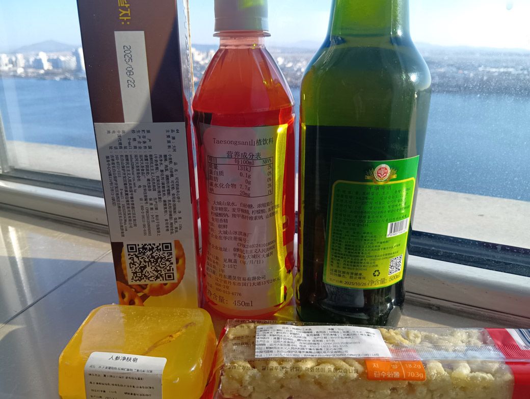 購入した商品。なお奥に見える街はすべて北朝鮮。ちなみに黄色の商品は石鹸で、北朝鮮に船で近づいた話を含め、詳細は別記事にまとめた（写真：筆者撮影）