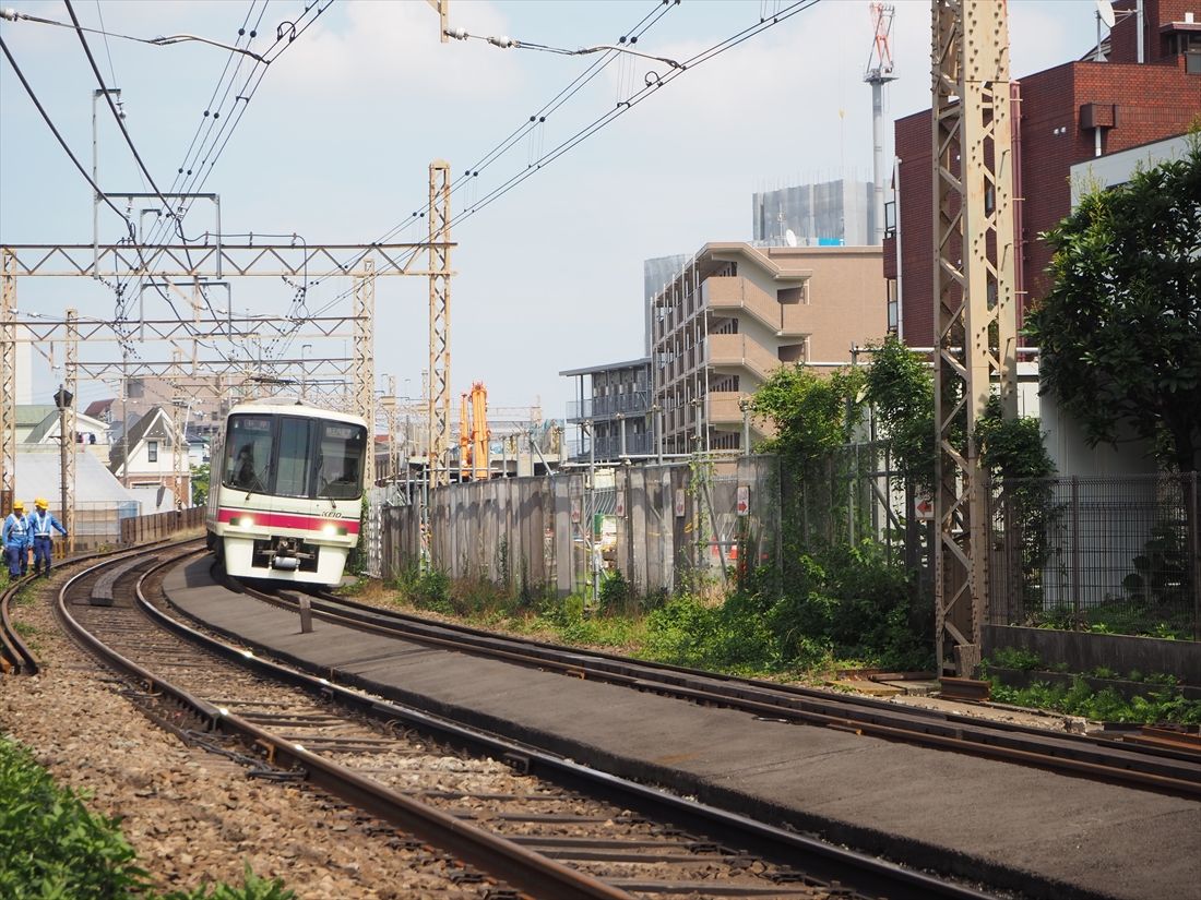 八幡山駅から芦花公園駅に向かって高架を下りてくる電車。右側では高架化に向けた引上線の撤去工事中（記者撮影）
