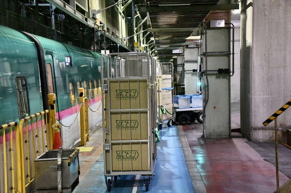 運行開始直前の訓練時の様子。荷物を載せた台車がAGVに牽引されてトラックへ向かう（記者撮影）