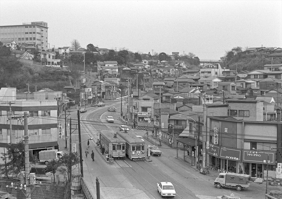 山元町への急坂（猿坂）の手前、石川町五丁目停留場ですれ違う横浜市電の車両。遠くにアーチ型の打越橋が見える＝1971年3月18日（写真：竹中洋一、しでんの学校提供）