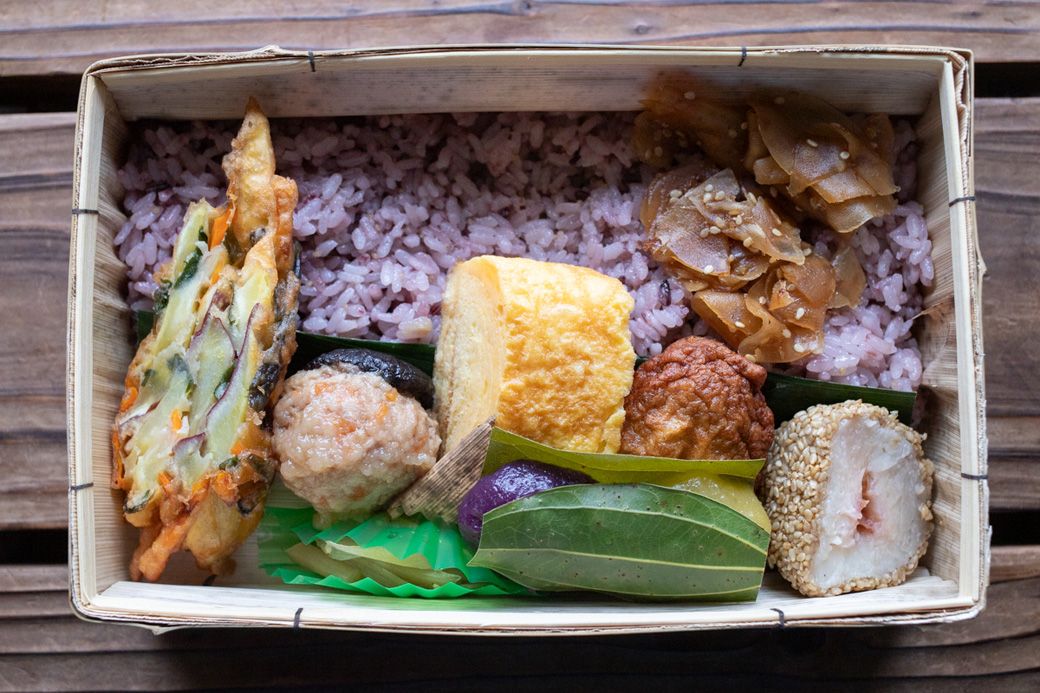 「花を待つ駅かれい川」（1800円）。黒米は桜の花、卵焼きは黄色の特攻花、梅肉は彼岸花、白いサトイモは野に咲くヒメジョオンをイメージしているという。けせん団子の爽やかな香りが清涼感を添えている（筆者撮影）