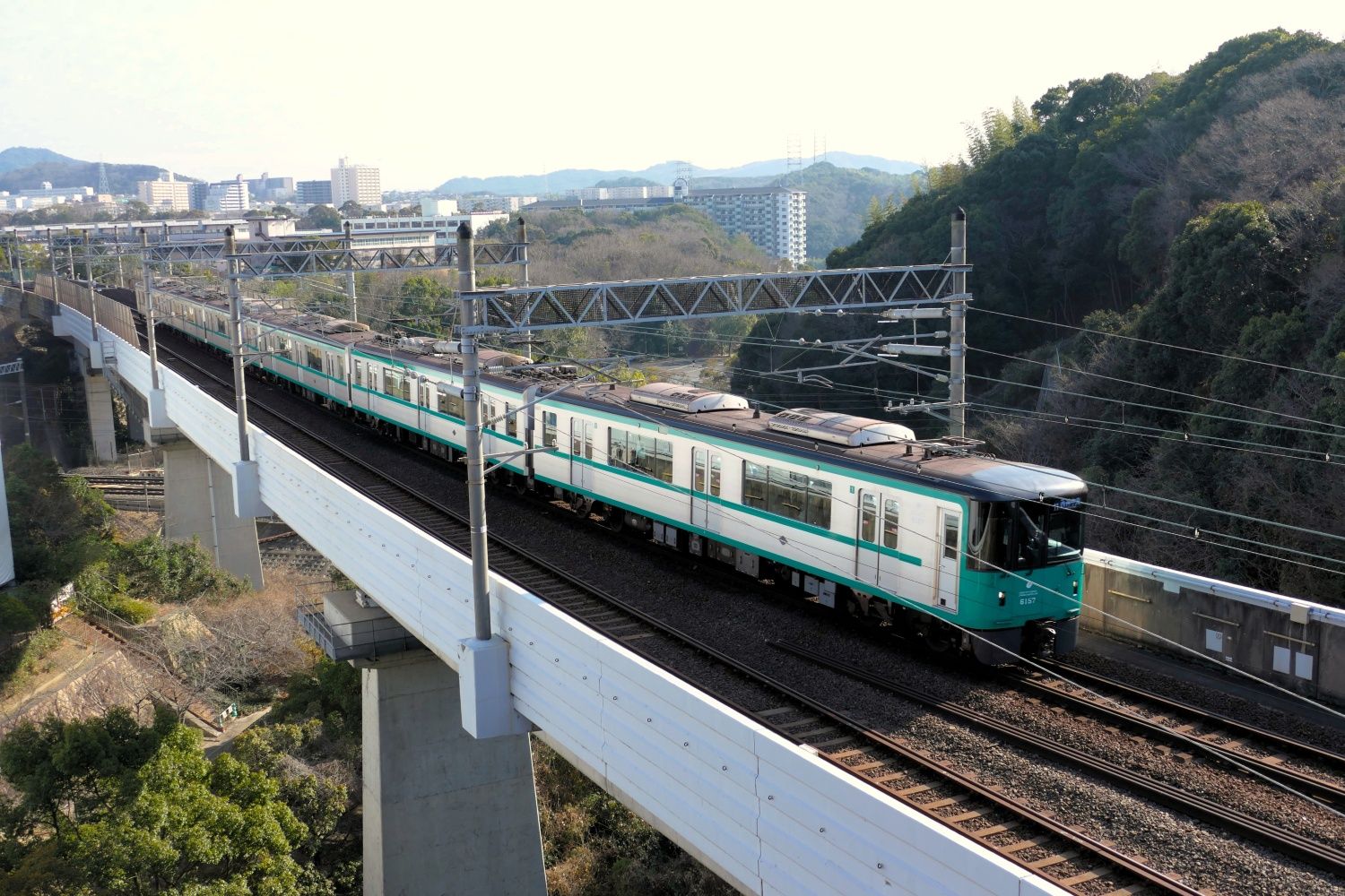 山陽新幹線の線路を高架でまたいで総合運動公園駅に到着する電車（編集部撮影）