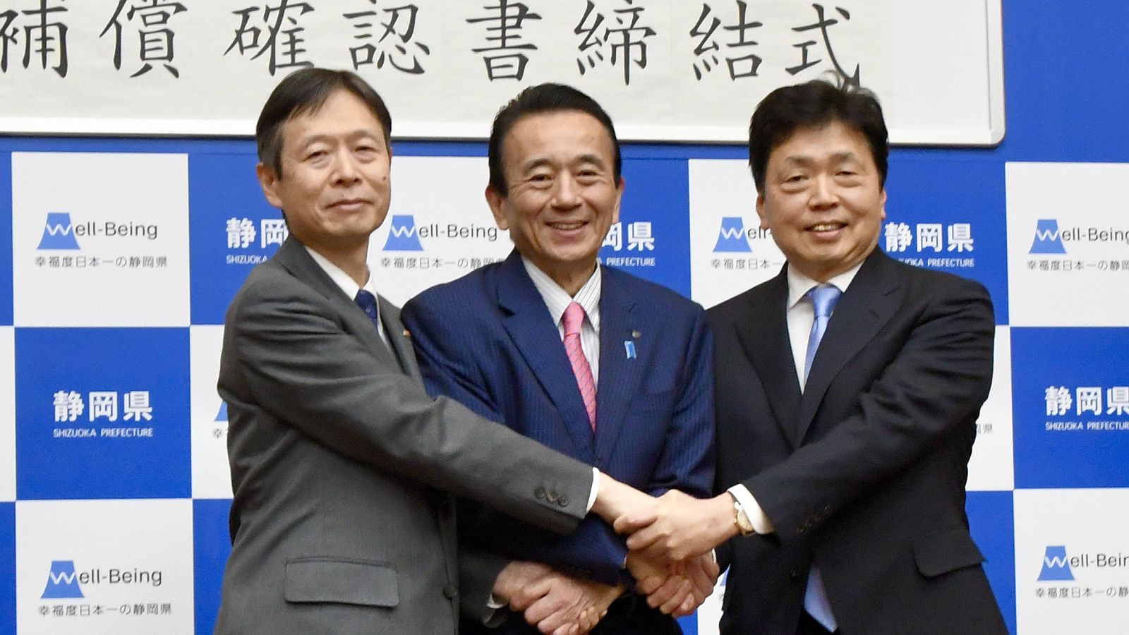 リニア工事の水資源問題に関する合意文書に署名した後、握手を交わす（左から）JR東海の丹羽俊介社長、静岡県の鈴木康友知事、国土交通省の水嶋智事務次官（記者撮影）