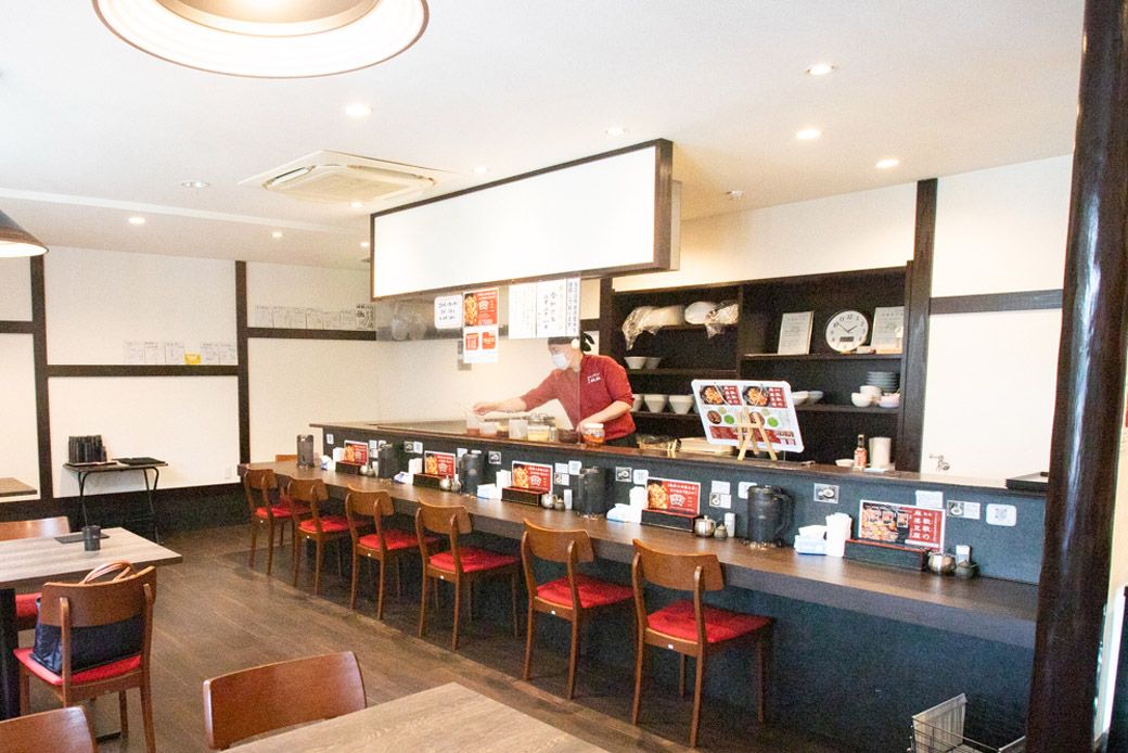 店内にはテーブル席とカウンター席が。調理風景も見えるようになっている。店の内装は、ラーメン屋の造りを参考に、女性ひとりでも気軽に入れる雰囲気を大切に考えたという（筆者撮影）