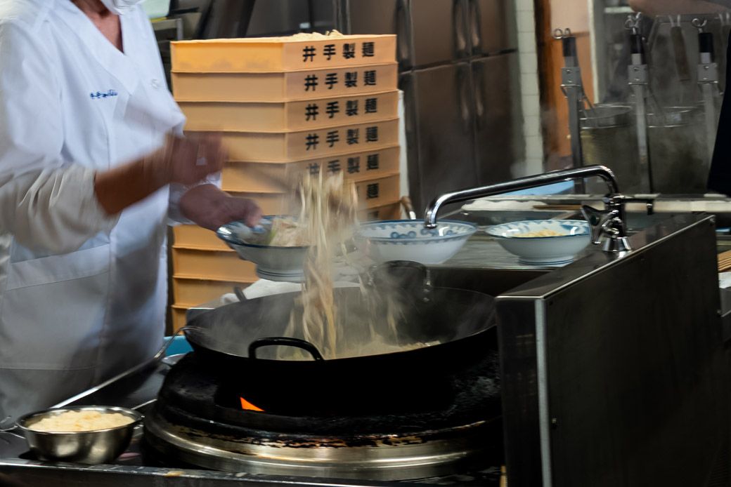 中華鍋の隣では麺が茹でられている。どんぶりに茹で上がった麺が入り、その上に具材が山盛りによそわれていく。野菜の量は計っておらず、目分量だという（筆者撮影）