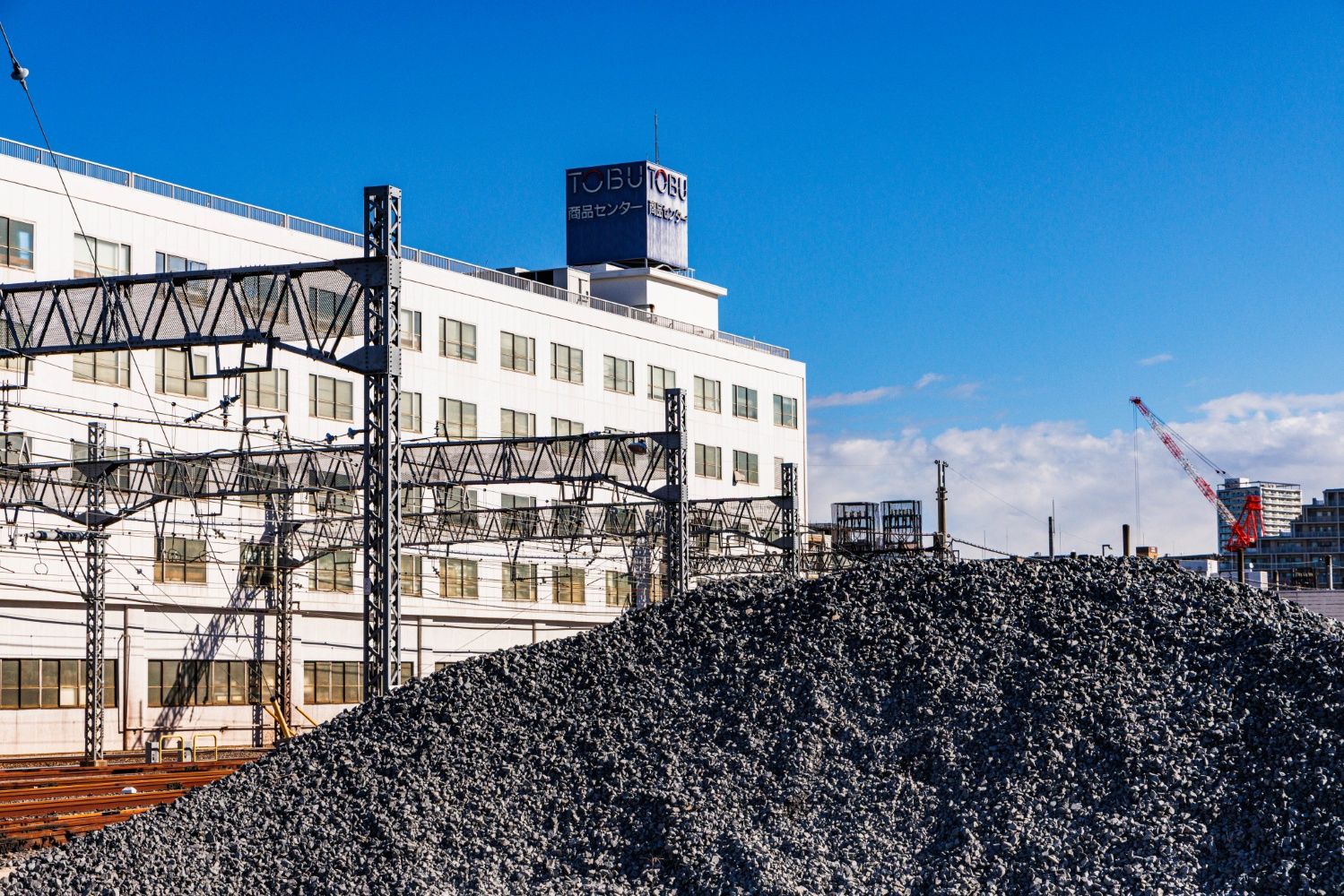 構内にはバラストを山と積んだ一角も。奥に見える東武百貨店の配送センターは貨物駅跡（撮影：鼠入昌史）