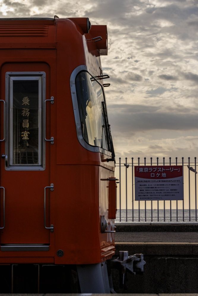 伊予灘を望む高浜線梅津寺駅にミカン色の電車がやってくる。この駅はドラマ『東京ラブストーリー』の聖地だ（撮影：鼠入昌史）