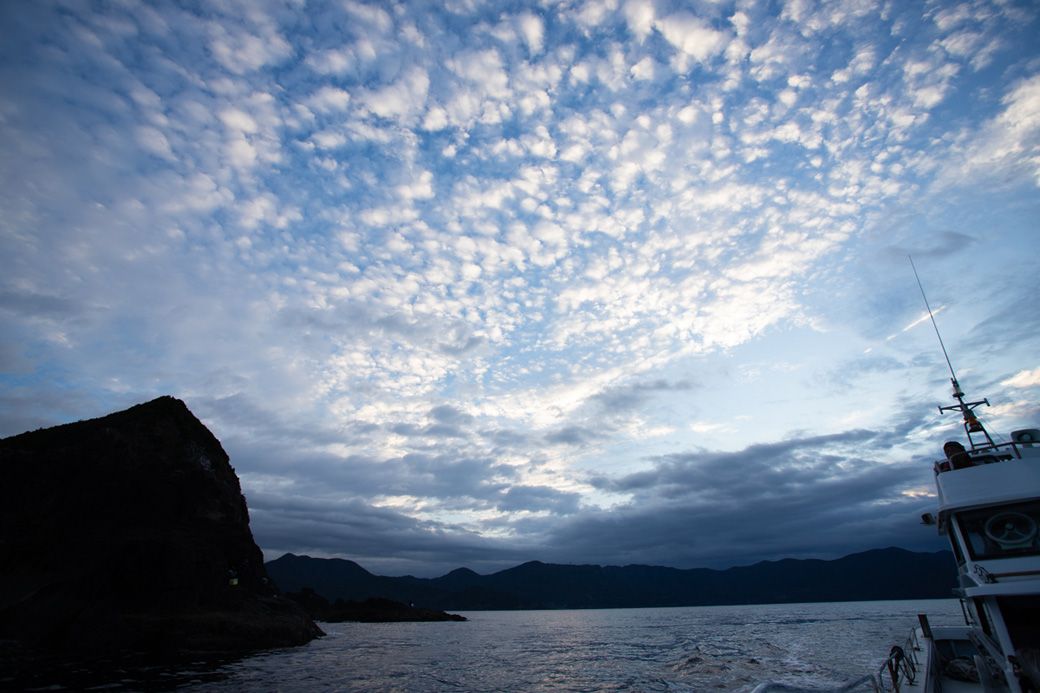 釣り客を順番に瀬に渡している間に、夜が明けてきた。海の上から見る夜明けの空が気持ちいい（著者撮影）