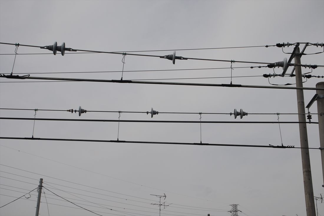 直流電化区間と交流電化区間のあいだにデッドセクションを設けることで電車の回路切替を行っている。架線にはデッドセクションに電気が流れないよう絶縁体が挿入されている（筆者撮影）