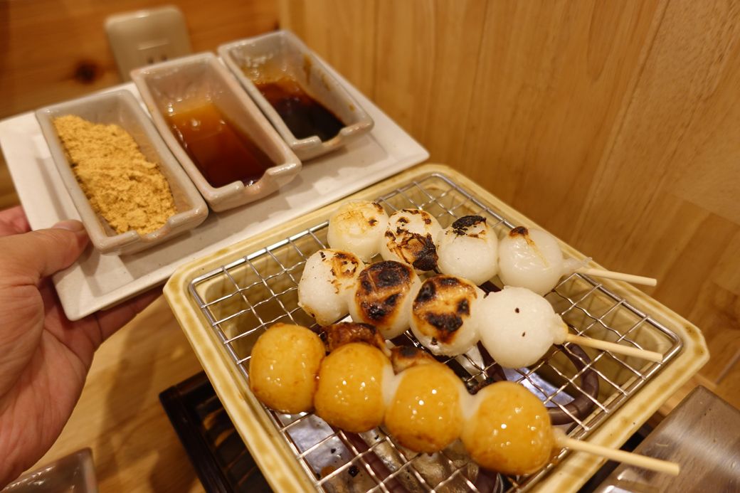 焼きあがった団子は、細長い容器に入ったきなこ・蜂蜜などをつけて食べる（筆者撮影）