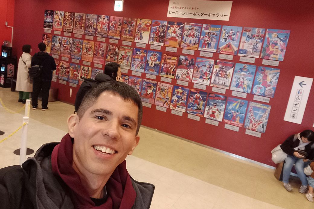 2023年の訪日時にシアターGロッソの戦隊ヒーローポスターをバックに自撮りしたヒベイロさん（写真：ヒペイロさん提供）
