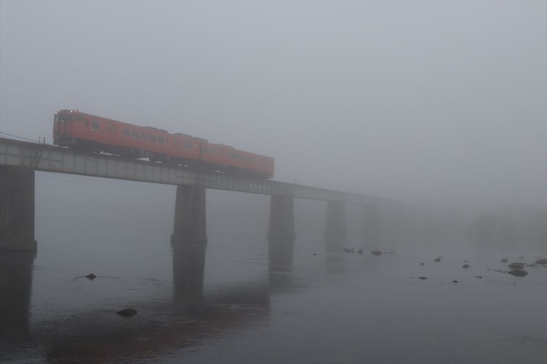 霧に煙る旭川橋梁とタラコ色の気動車（撮影：南正時）