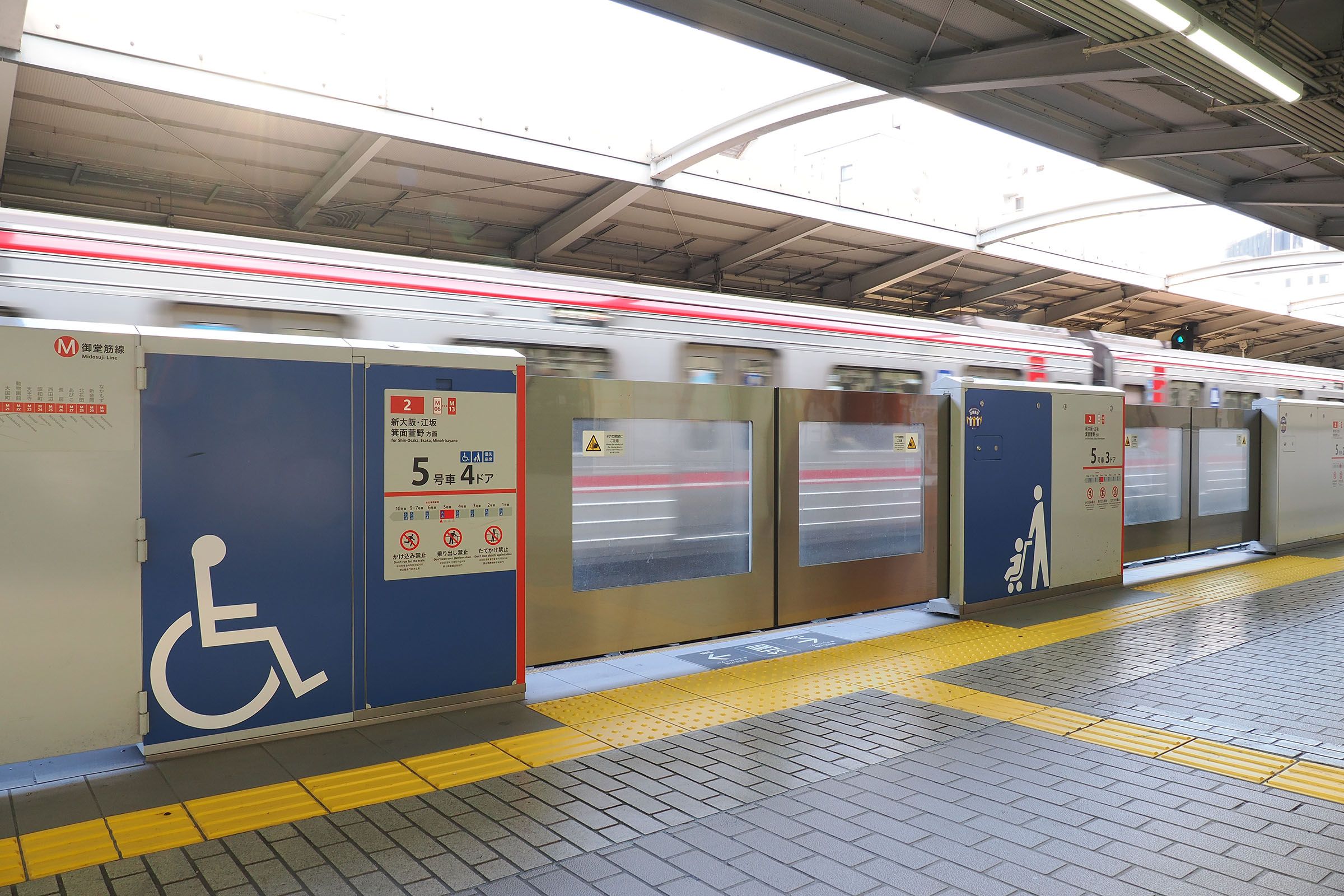 車いすの単独乗降を可能とした車両の車いすスペース付近であることを示す、御堂筋線のホームドアの表記（撮影：伊原薫）