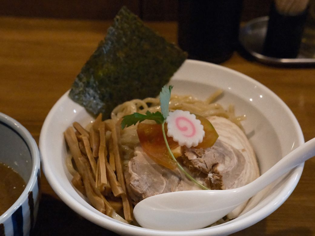 蕃茄とはトマトのこと。太麺に三つ葉やトマトが添えられていて、魚介ベースのつけ汁には柚子が入っている（筆者撮影）