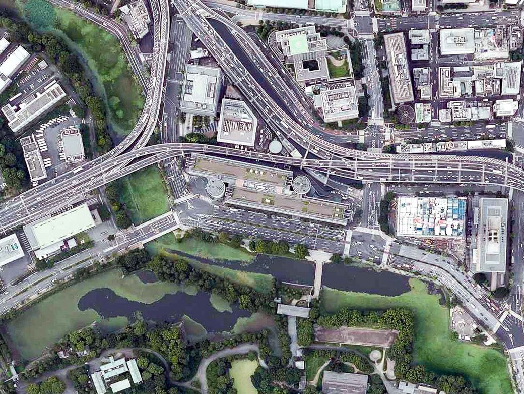 上空から見たビル。長細いオフィス部分の端に、ふたつの円筒コアがある（国土地理院撮影の空中写真（2019年撮影）を加工して筆者作成）