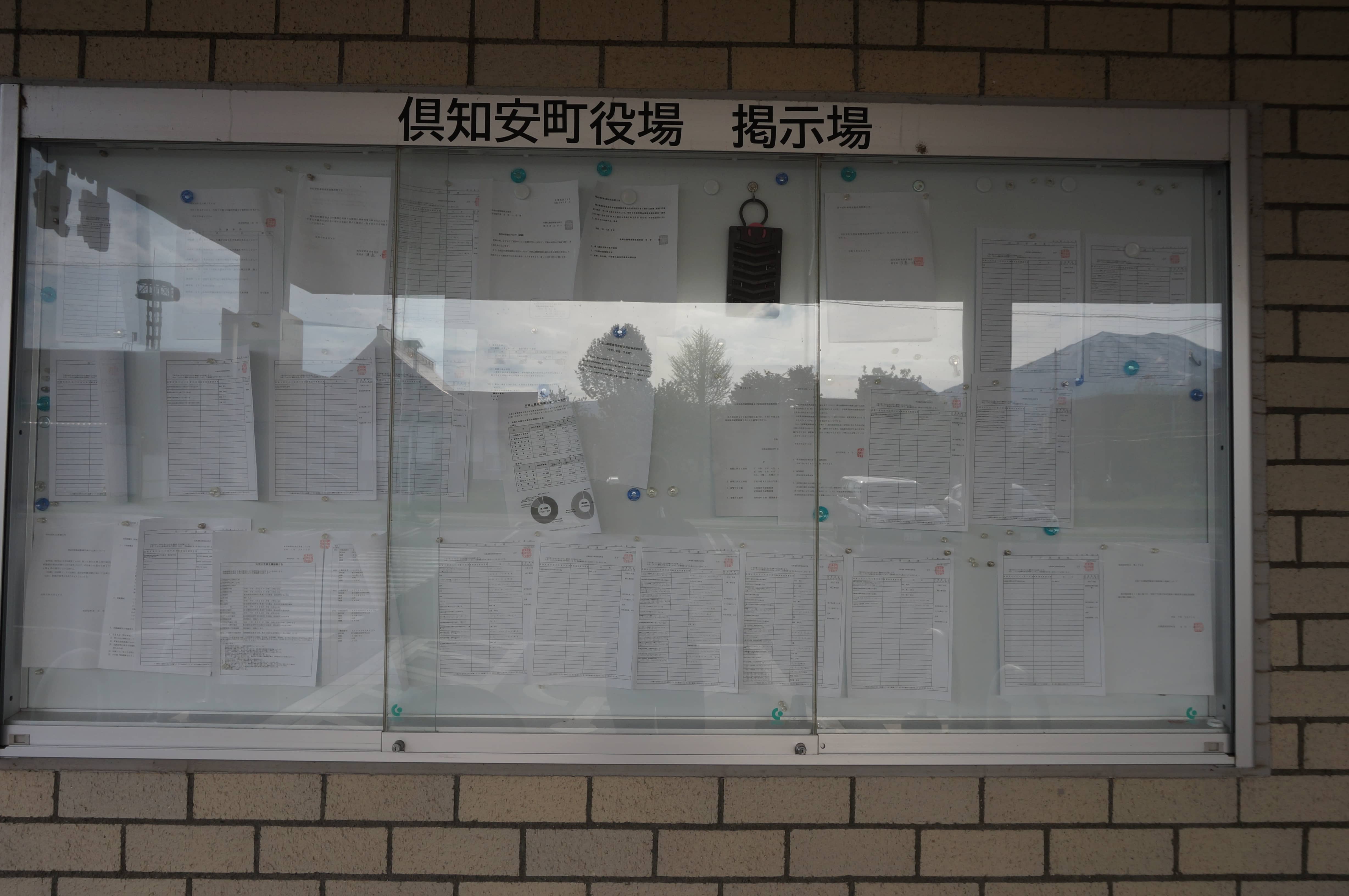 公示通達が重なるように貼られた倶知安町役場の掲示場（写真：筆者撮影）