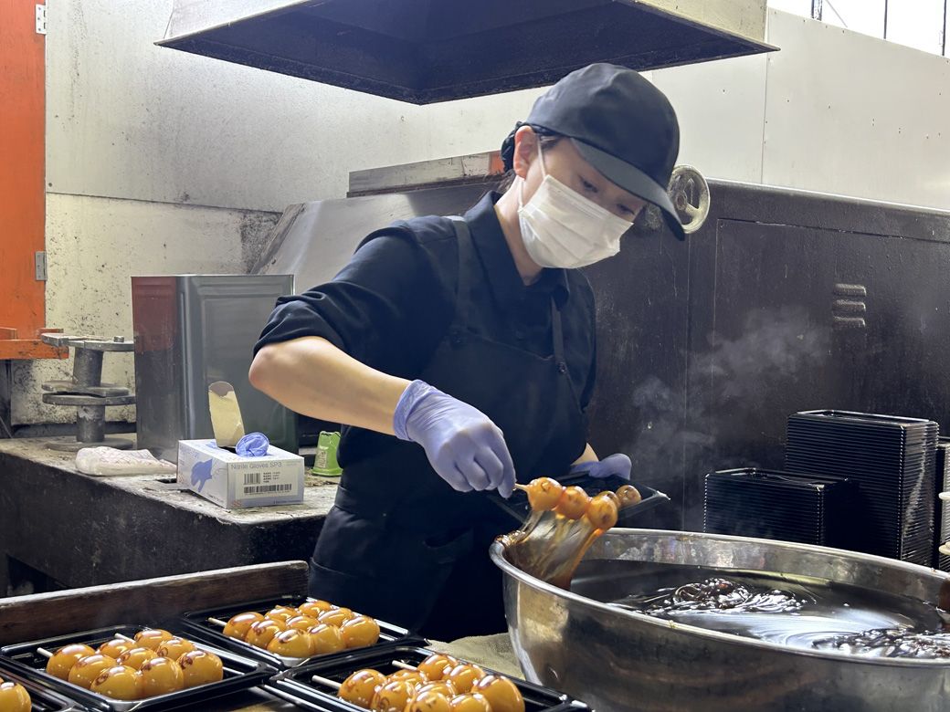 団子にみたらしあんをからめていく沙邦莉さん（筆者撮影）
