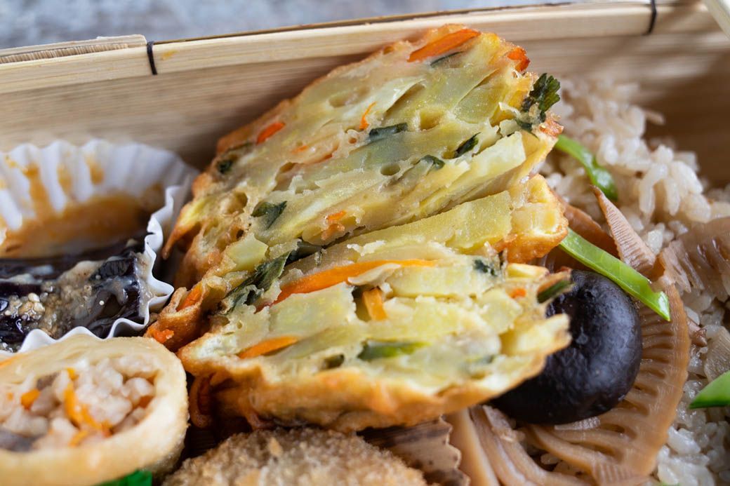 鹿児島の郷土料理の代表格・ガネ。サツマイモの細切りを粉と合わせて揚げる。作り方は地域、人によってさまざまだが、水を一切使わずに作るのが山田さんのやり方。サツマイモ、ニンジン、ニラを切り、卵と砂糖、醤油、塩を混ぜておくと野菜の水分が出てくるので、そこに小麦粉を絡めてから油で揚げている（写真：筆者撮影）